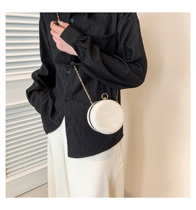 Detail of a vintage marble pattern round clutch with gold chain strap on model