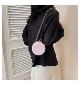 Detail of pink pearlescent shell texture on a round evening bag with gold chain strap