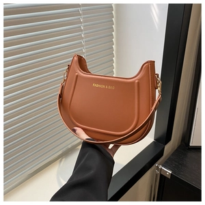 Dettaglio borsa a mezzaluna marrone con fibbia dorata e scritta decorativa fashion