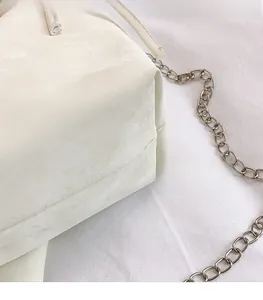 Detailed close-up of stitching and matte PU leather texture on a white crossbody bag