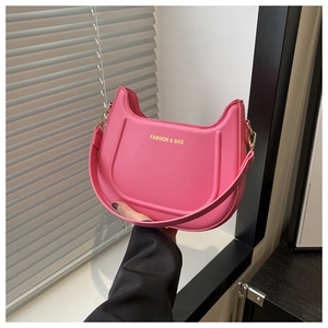 Dettaglio della borsa a sella in pelle rosa con ganci dorati e scritta Fashion & Bag