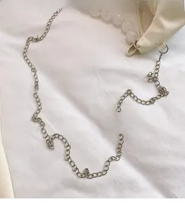 Macro shot of silver metal chain strap with resin beads on a soft white cream handbag
