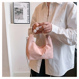 Detail of pink PU leather handbag featuring white bead handle and gold chain strap