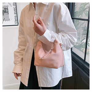 Detail showing the light pink matte leather texture and delicate gold chain of the hobo bag