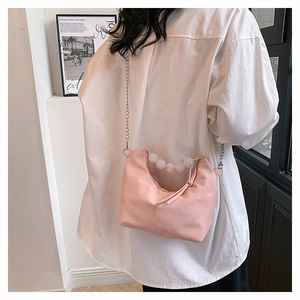 Detail of pink pearl handbag with silver chain strap and beaded handle on a model
