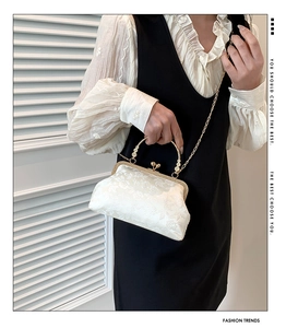 Detailed close-up of vintage white jacquard crossbody bag with pearl handle and chain strap