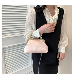 Light pink vintage kiss-lock bag with floral jacquard pattern worn by a model