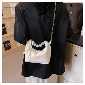 Detail of cream white PU shoulder bag featuring marble bead handle and silver chain strap