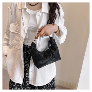 Chic black velvet handbag with amber bead handle and silver chain strap on a model