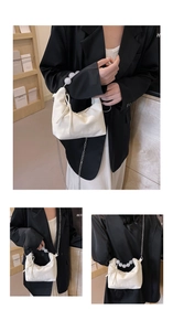 Detail of white satin cloud bag with clear beaded handle and metal chain strap