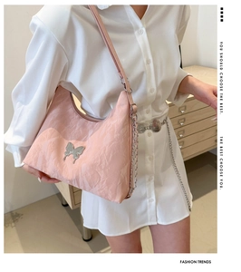 Détail du sac bandoulière rose avec papillon en métal et texture plissée élégante