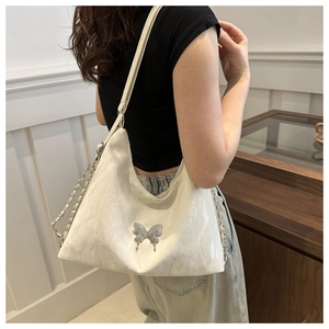 Détail du sac bandoulière en PU blanc avec texture froissée et boucle papillon argentée
