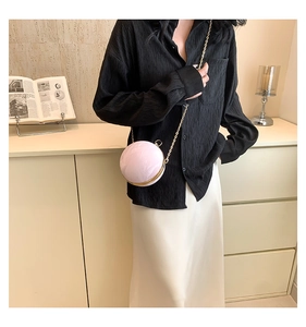 Detail of pink marble textured round chain bag with elegant gold metal frame and slim strap