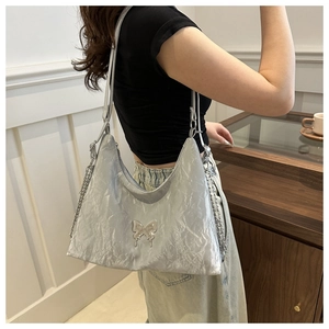 Silver metallic pleated tote bag featuring a decorative metal butterfly and chain strap