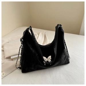 Détail du sac cabas en daim noir avec breloque papillon en métal et bandoulière chaîne