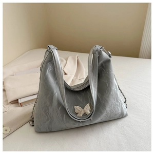 Détail du sac cabas argenté avec texture froissée et décoration papillon en relief