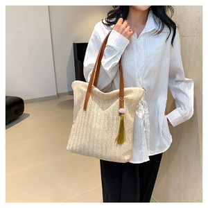 Minimalist straw woven tote bag with brown leather straps and gold velvet tassel pendant