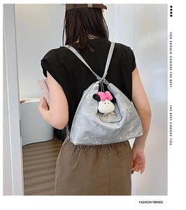 Detail view of silver metallic backpack featuring a white plush rabbit charm and bow