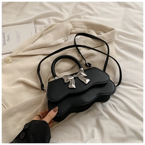 Détail du sac à main noir avec boucle nœud argenté et base au design ondulé unique