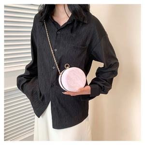 Elegant round pink mini bag with gold chain strap shown on a minimalist model background
