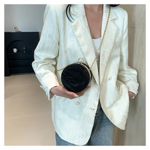 Chic black round crossbody bag with pleated texture and gold chain strap shown on model