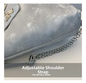 Detail of adjustable metal chain strap and mottled texture on grey crossbody bag