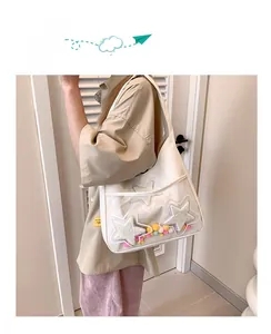 Détail du sac cabas blanc avec poche PVC transparente décorée d'étoiles et de pompons colorés