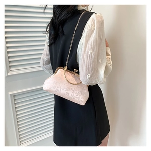 Borsa a mano in broccato rosa con ricami floreali e catena d'oro indossata dal modello