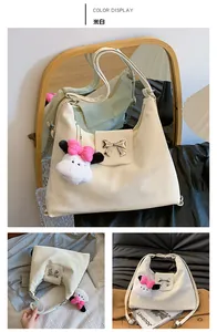 Detail of off-white shoulder bag featuring a metal bow clasp and cute panda charm