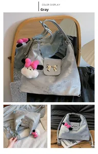 Close-up of grey crossbody bag with silver bow buckle and plush charm detail