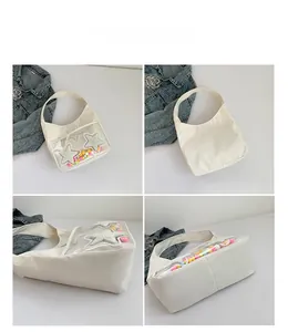 Vue détaillée du sac demi-lune blanc avec poche PVC et pompons colorés