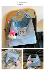 Detail of light blue shoulder bag featuring gold bow hardware and plush charm pendant