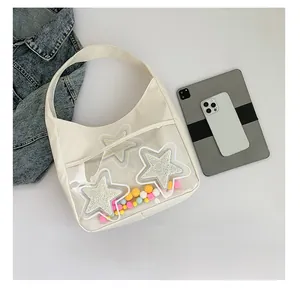 Détail de la capacité du sac bandoulière blanc avec étoiles à côté d'une tablette