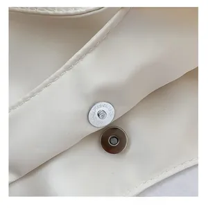 Détail du fermoir magnétique en métal et des coutures sur un sac en toile blanc