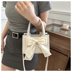 Detail of white rectangle handbag featuring a large mesh bow and matte leather texture
