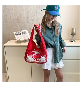 Détail du sac cabas en toile rouge avec écussons étoiles et boules en peluche colorées