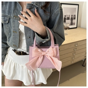 Primo piano della borsa rosa con grande fiocco in organza e delicata trama in PU