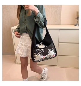 Détail du sac cabas à étoiles noires avec boules en peluche dans une poche en PVC