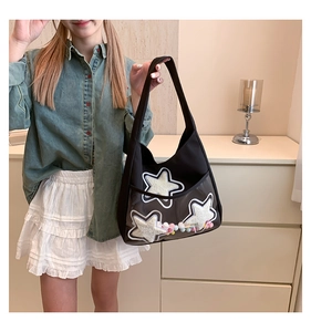 Détail du sac cabas en toile noire avec patchs étoiles et pompons colorés décoratifs