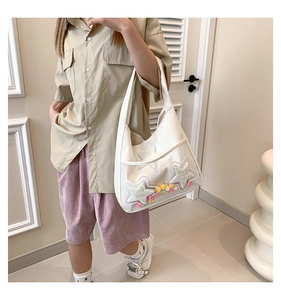 Détail du cabas en toile blanche avec poche PVC et écussons étoiles en peluche douce