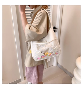 Détail du sac cabas blanc avec poche transparente, étoiles en peluche et pompons