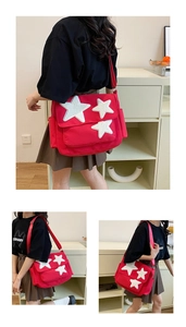 Detail view of red canvas crossbody bag featuring three plush white star appliques and side pockets
