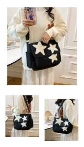 Detail of black canvas messenger bag featuring plush star patches and wide shoulder strap