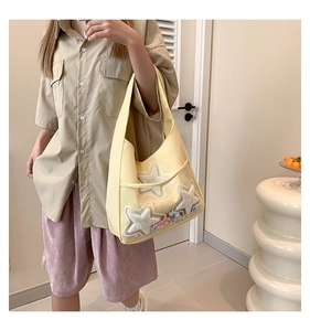 Détail du sac jaune avec étoiles en peluche et pompons colorés dans une poche transparente