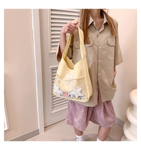 Détail du sac en toile avec étoiles en peluche et pompons colorés dans la poche PVC