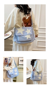 Detail of light blue canvas messenger bag with white plush stars and adjustable strap