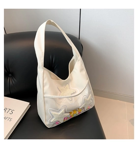Détail du sac cabas crème avec étoiles en peluche et pompons colorés sous couche PVC