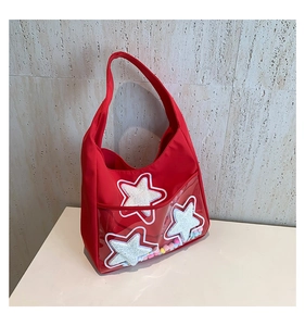 Détail du sac rouge en nylon avec étoiles à paillettes et poche transparente à pompons