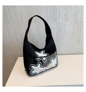 Détail du sac noir avec couche PVC transparente, étoiles et pompons colorés décoratifs