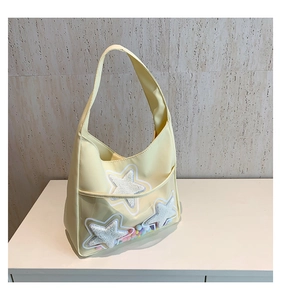 Détail du sac bandoulière jaune clair avec étoiles en peluche et pompons de couleur